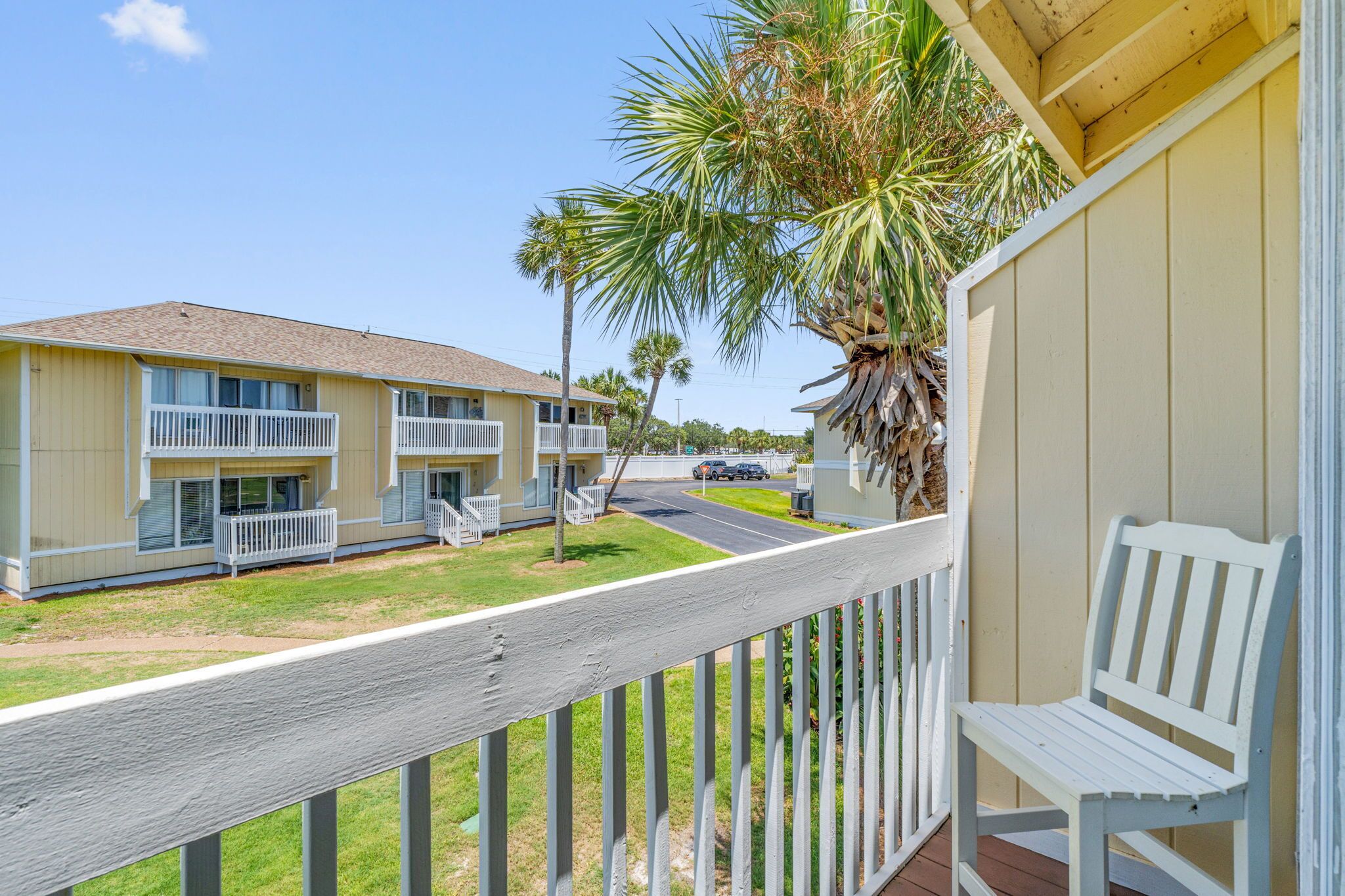 A motel with a wooden deck and a white bench.
