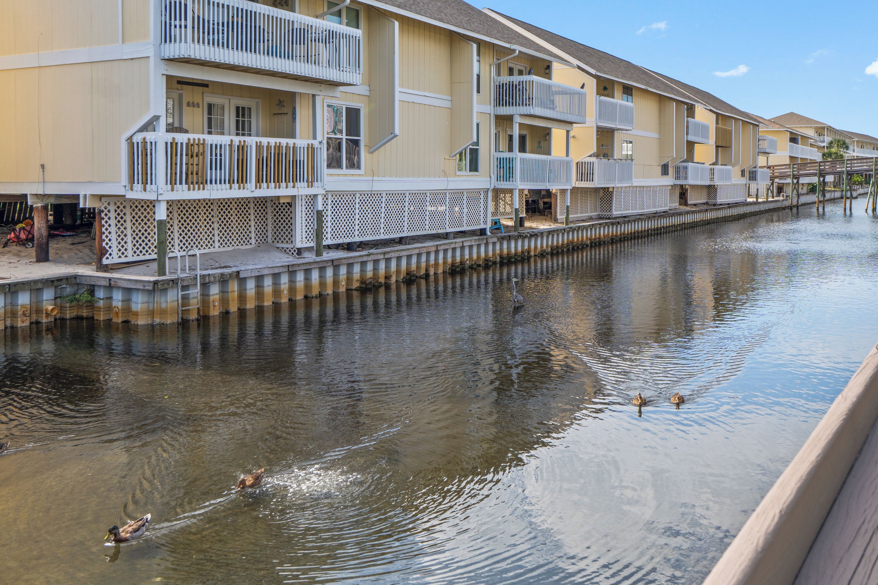 A waterfront hotel with balconies, a dock, and a canal with ducks.