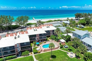 A hotel with a rooftop pool, a beach view, and a well-maintained lawn.
