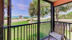 Un balcone con vista sulla spiaggia, una torretta di salvataggio e una zona verde.