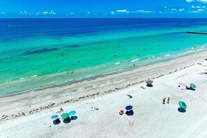 Una playa con aguas turquesas cristalinas, una orilla arenosa y varias sombrillas.