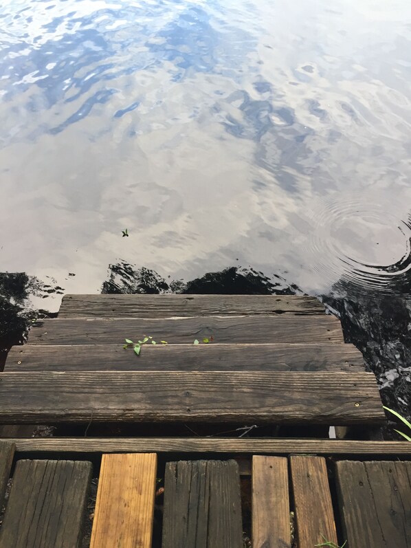 Une jetée en bois s’étendant dans une étendue d’eau, dont la surface est légèrement agitée.
