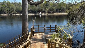 Una terraza de madera que da a un lago, con un banco y un flotador.