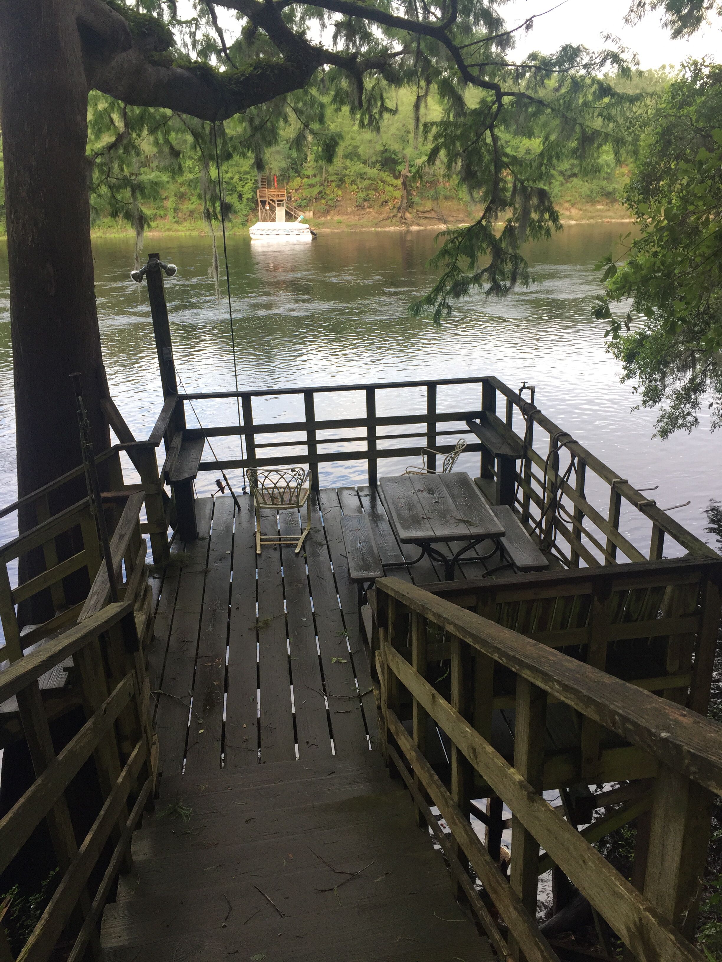 A wooden dock with a picnic table and benches overlooking a calm lake.