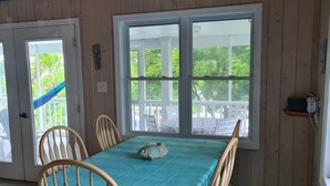 A dining area with a table covered in a teal tablecloth, surrounded by wooden chairs. - Beautiful home with wifi, tv, A/C, private dock, & backup generator power (Hope Town, Abaco)