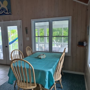 A dining area with a table covered in a teal tablecloth, surrounded by wooden chairs.