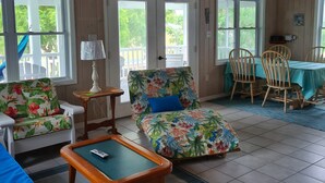 A cozy room with a ceiling fan, a pool table, a floral sofa, and a dining area with chairs and a table. - Beautiful home with wifi, tv, A/C, private dock, & backup generator power (Hope Town, Abaco)