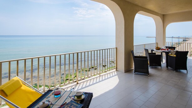 A balcony with a view of the sea, furnished with chairs and a table, and a dining setup. - Apartment/ flat - Scicli (Donnalucata)