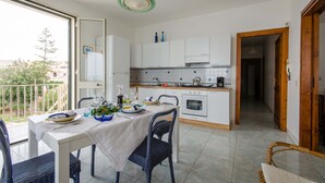 A modern kitchen with white cabinets, a dining table with chairs, and a view of the outside. - Apartment/ flat - Scicli (Donnalucata)