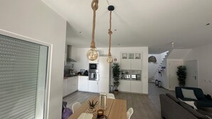 Ett modernt kök med vita skåp, ett matbord med stolar och en trappa som leder till ett annat våningsplan.