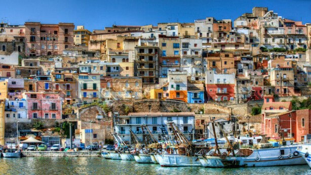 Un poble costaner amb edificis de colors i embarcacions amarrades al port.