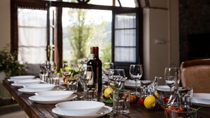 A dining table set with plates, glasses, and a bottle of wine, with a view of greenery outside. - Panorama, relax in farmhouse 30 kw from Volterra e 40 from Pisa airport (Chianni)