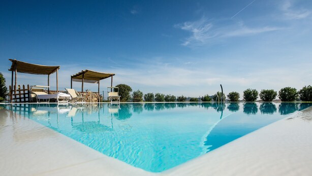 A clear blue pool with lounge chairs and shaded areas, surrounded by greenery. - Panorama, relax in farmhouse 30 kw from Volterra e 40 from Pisa airport (Chianni)