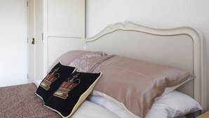 Ein Bett mit weißem Kopfteil, zwei Kissen und einer braunen Decke.