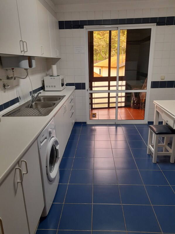 A compact kitchen with a washing machine, a sink, and a microwave.