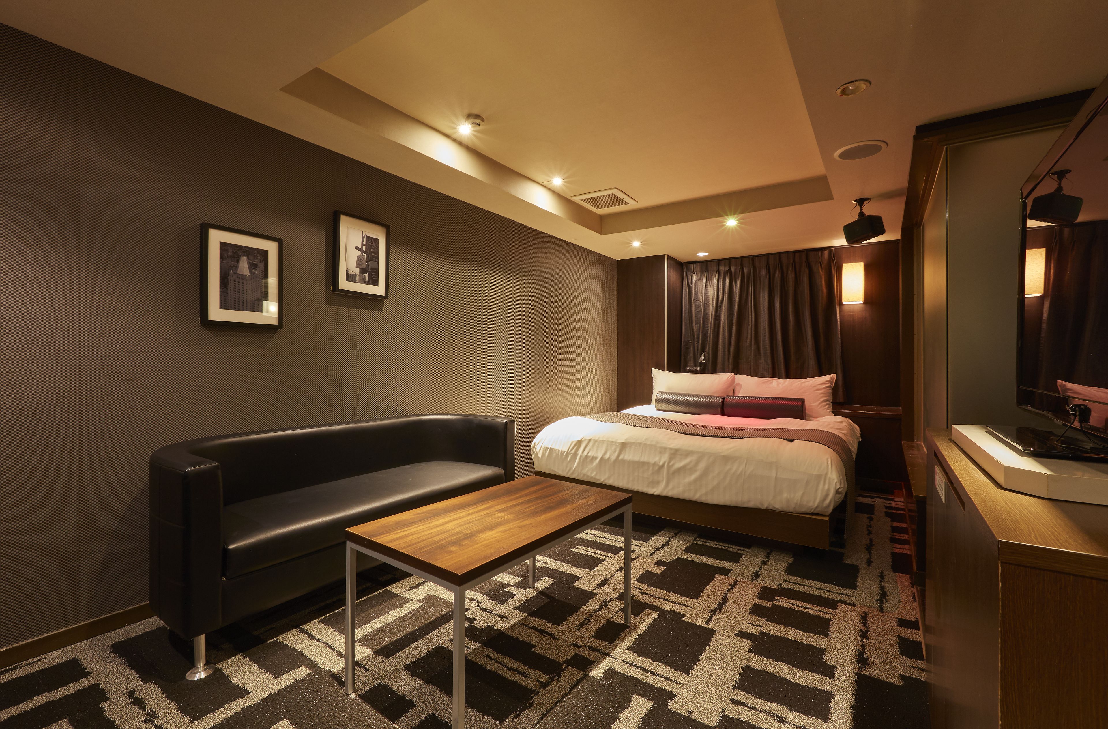 Una habitación de hotel moderna con una cama, un sofá, una mesita de madera y un televisor.
