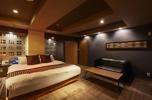 Une chambre d’hôtel avec un lit, un canapé, un banc en bois et une enseigne fixée au mur sur laquelle on peut lire « ROYAL ».