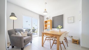 Un soggiorno moderno con un divano grigio, un tavolo da pranzo in legno e un'ampia finestra con tende.