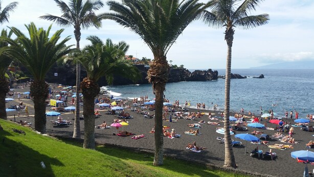 Una spiaggia affollata con molti ombrelloni e persone che prendono il sole.