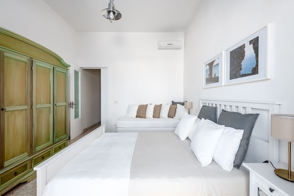 A bedroom with a large bed, a white wardrobe, and two framed pictures on the wall.