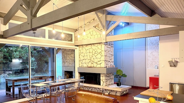 Ein modernes Interieur mit Kamin aus Stein, einer Essecke mit Metallstühlen und einem Ledersofa.
