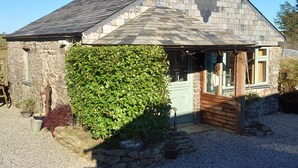 A stone cottage with a green ivy-covered wall, a wooden door, and a gravel driveway. - Stunning uninterrupted moorland views over lake and Rough Tor (Advent)