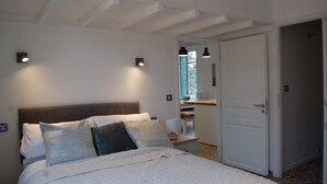 Ein Schlafzimmer mit Bett, Nachttischlampen, einem Nachttisch, einer Tür und einem Fenster.