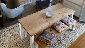 Ein gemütliches Wohnzimmer mit einem blauen Sofa, einem Holztisch und einem Esstisch mit Bänken.