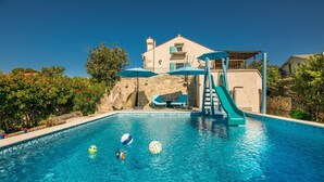 A swimming pool with a slide, lounge chairs, and umbrellas. - Awesome home in Kornic (Kornic)