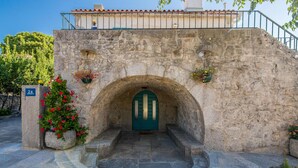 A stone building with a green door, a stone staircase leading up to it, and flower pots on the walls. - Awesome home in Kornic (Kornic)