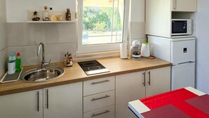 A compact kitchen with a sink, stove, microwave, and a window with a view of greenery. - 1 bedroom gorgeous home in Marcana (Marcana)