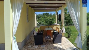 An outdoor patio with a table and chairs, a grill, and a view of greenery. - 1 bedroom gorgeous home in Marcana (Marcana)