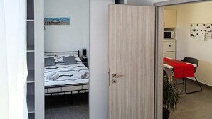 A bedroom with a bed, a desk with a red tablecloth, a chair, a microwave, and a bulletin board. - 1 bedroom gorgeous home in Marcana (Marcana)