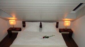 A neatly made bed with white linens, two bedside lamps, and a single rose on the bed. - Modern, exclusive and bright apartment in Rees (Rees)