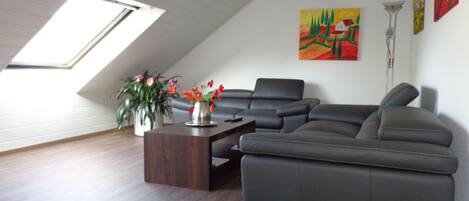 Un salon moderne avec un canapé d’angle, une table basse et une lucarne.