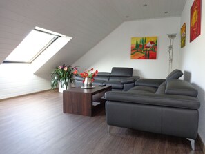 A modern living room with a sectional sofa, a coffee table, and a skylight.