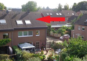 A residential area with houses, a garden, and a red arrow pointing to a house with a tiled roof and skylights.