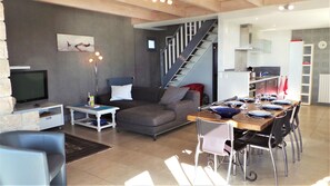 A modern living room with a sofa, TV, and dining area set up for a meal.