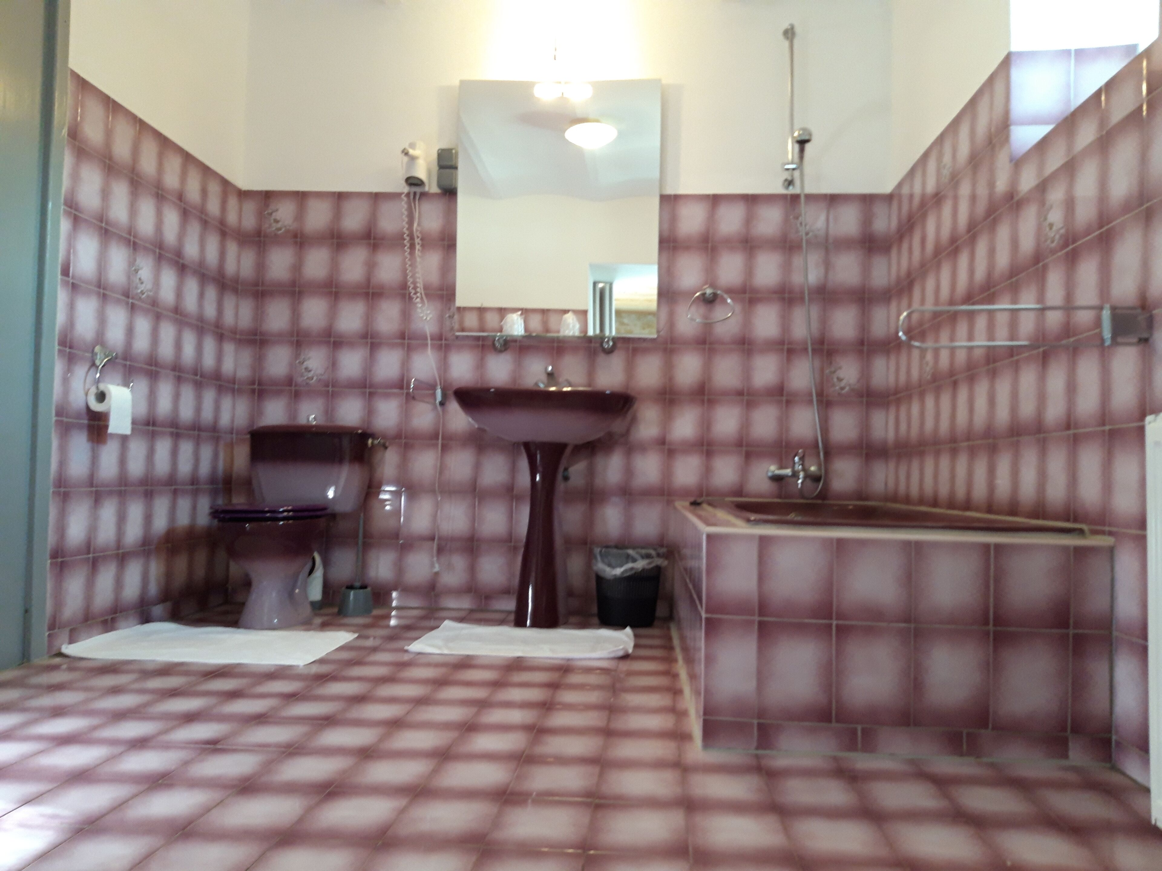 Un baño con piso de estampado de cuadros, un lavamanos pedestal, un inodoro y una bañera.