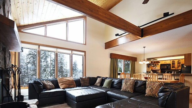 A spacious living room with a large sectional sofa, a fireplace, and a view of a snowy forest through large windows. - 61 Jabberwocky Private vacation home 5 bedroom, pet friendly clubhouse amenities (Fraser)