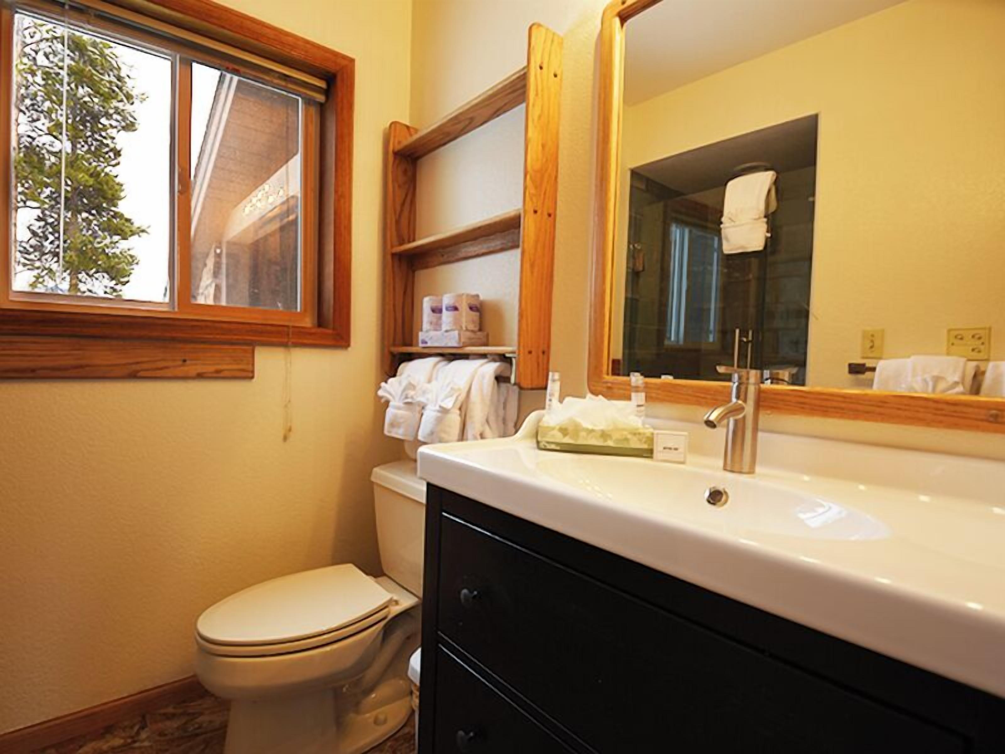 Un baño con inodoro, lavabo, espejo y ventana.