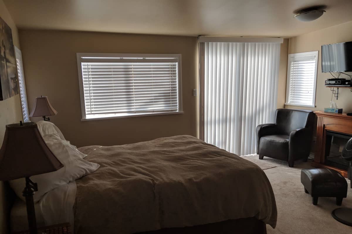 A bedroom with a bed, a chair, a desk, and a television.