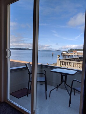 A balcony with a view of a waterfront, including a dock and a building.