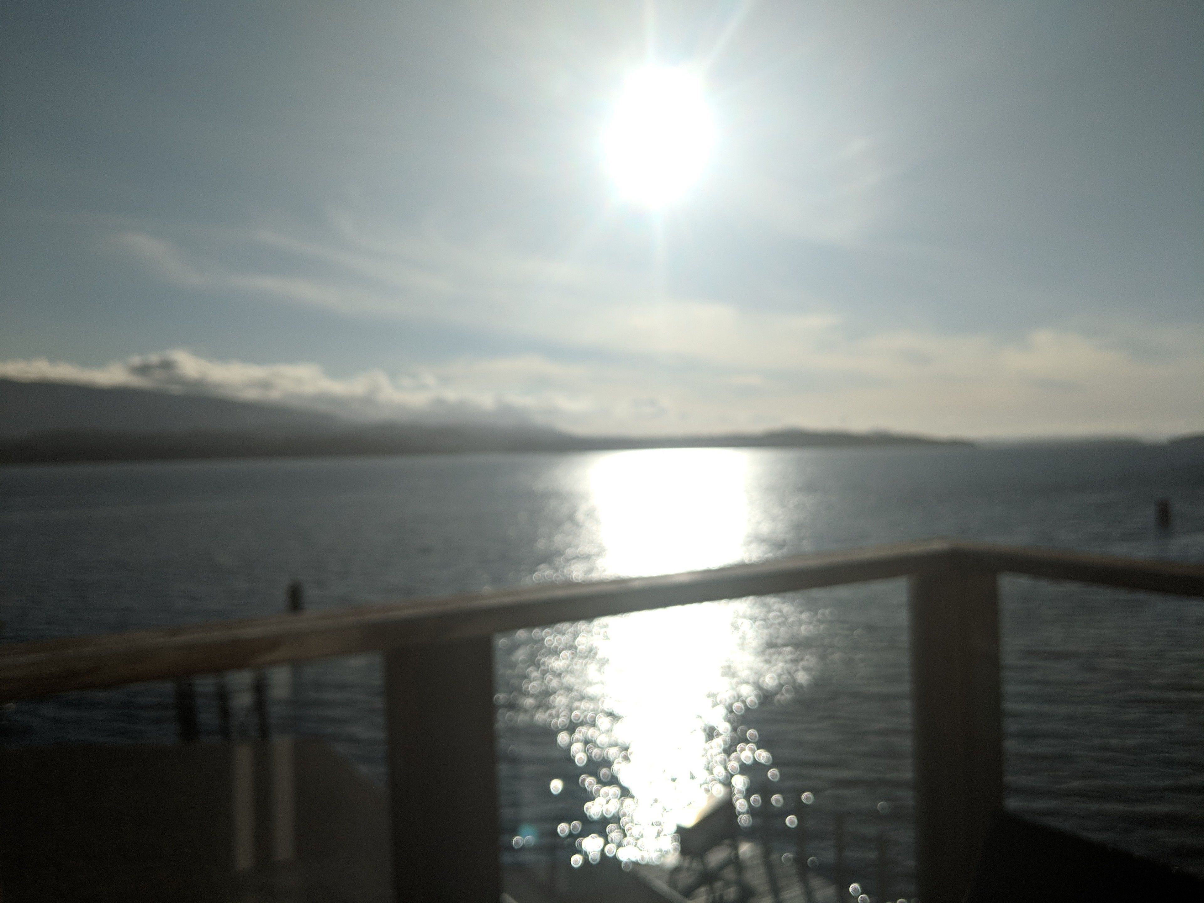 A body of water with a railing in the foreground.