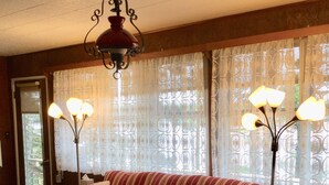 Un salón con un sofá a rayas, dos mesas de vidrio y una araña.