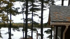 Una terraza de madera que conduce a una cabaña con vistas a un lago rodeado de árboles.