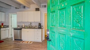 Una cucina moderna con mobili bianchi, lavastoviglie e macchina da caffè.