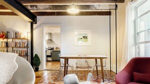 Een moderne woonkamer met een eethoek, houten vloeren en een groot raam.