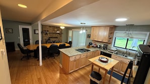 A spacious kitchen with a large island, wooden cabinets, and a stone fireplace. - Large private home on wooded acreage (Robbinsville)