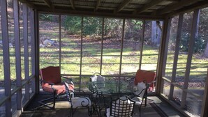 A covered patio with a glass table and chairs, overlooking a grassy yard. - Large private home on wooded acreage (Robbinsville)